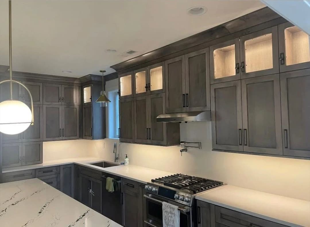 Modern kitchen with gray cabinets, white countertops, and stainless steel appliances.