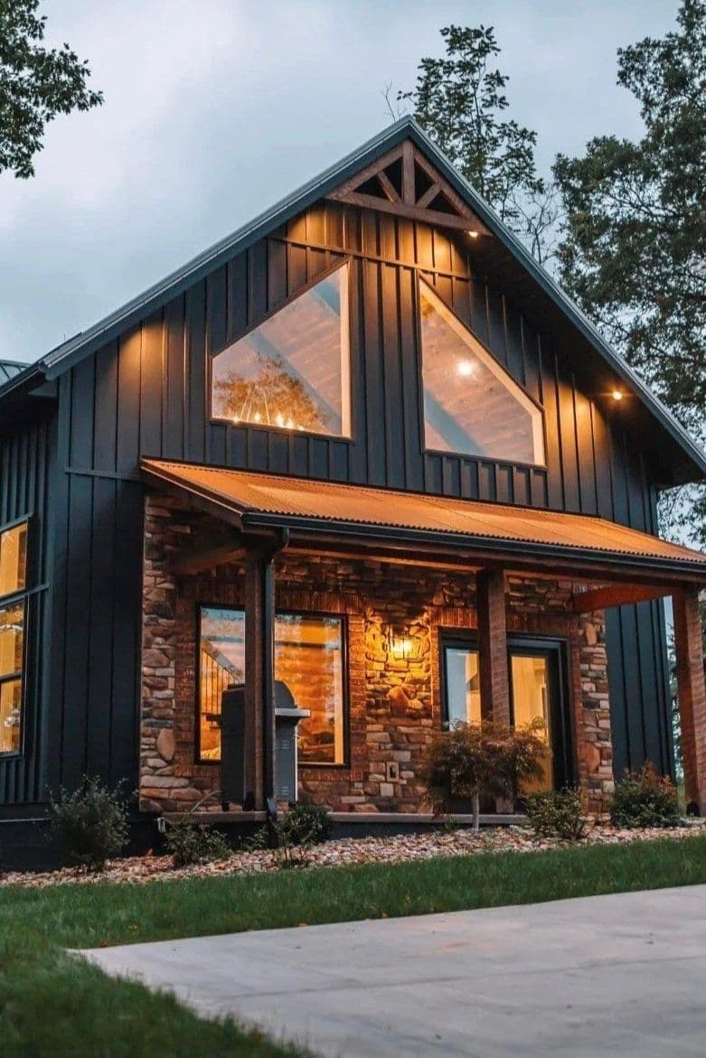 Black modern house with stone accents, large windows, and landscaped front yard at dusk.
