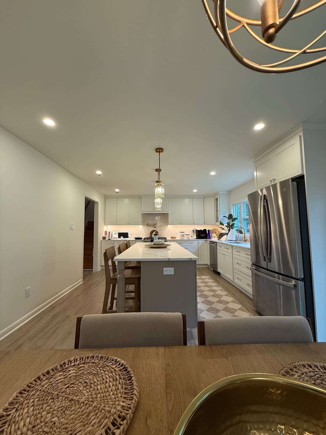 Modern kitchen with white cabinets, island, stainless steel appliances, and dining table.