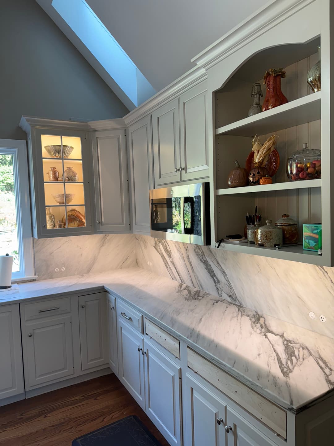 Modern kitchen featuring grey cabinetry, marble countertops, and well-organized shelves.