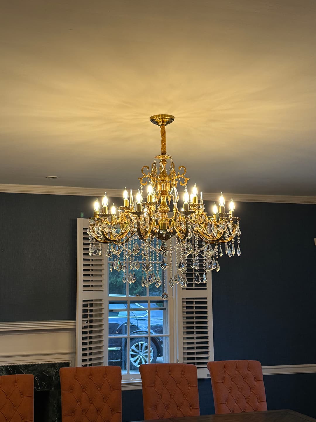 Elegant crystal chandelier illuminating a dining room with blue walls and a wooden table.